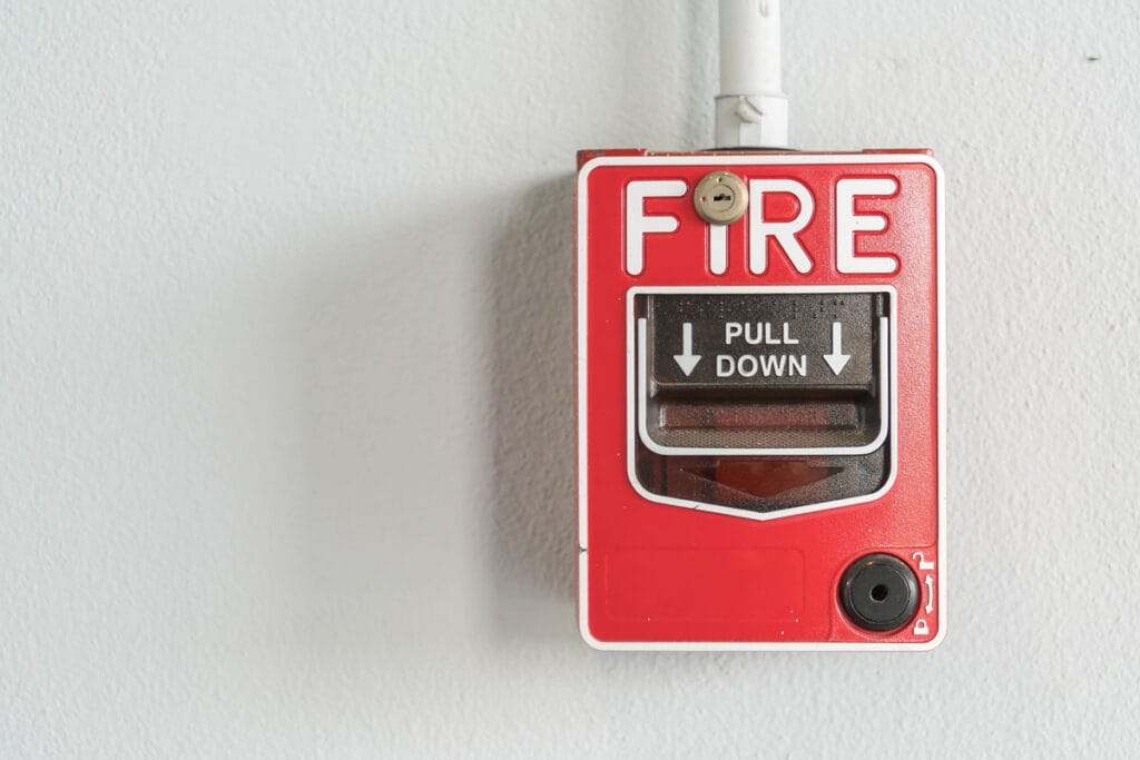 Bot&oacute;n de alarma de incendios rojo con la inscripci&oacute;n "FIRE PULL DOWN"